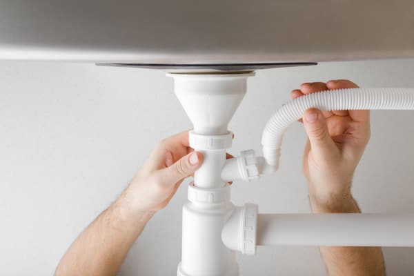 A person installing a dishwasher hose